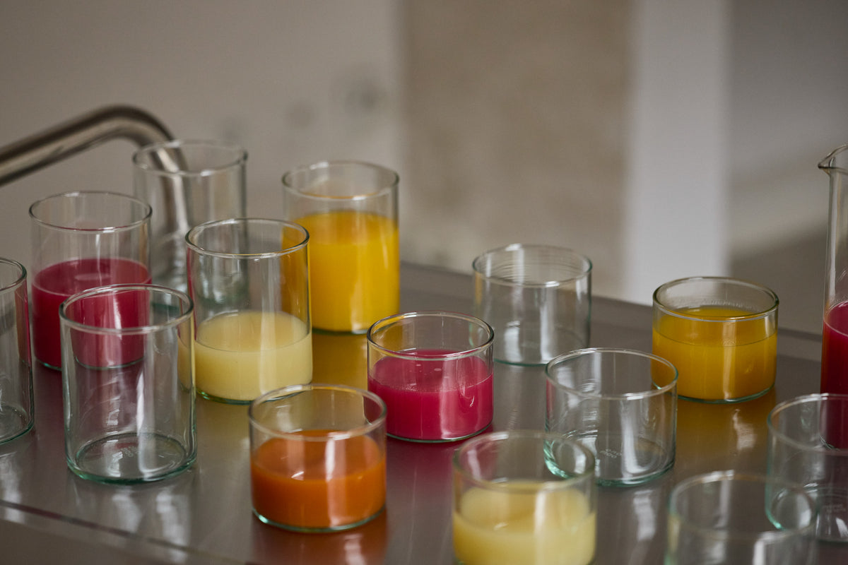 Mundgeblasene Trinkgläser mit Saft und Wasser auf einem verchromten Servierwagen von der Seite